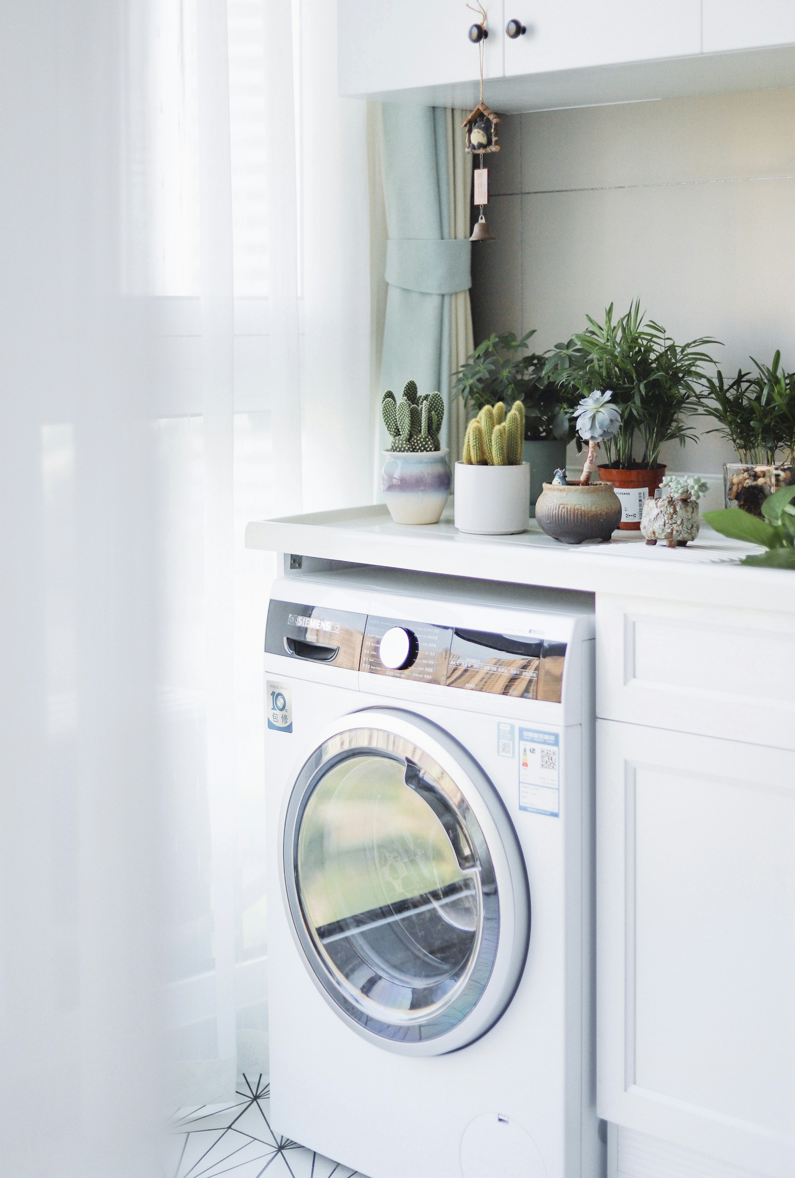 White front-load washing machine installed beside a white wooden cabinet