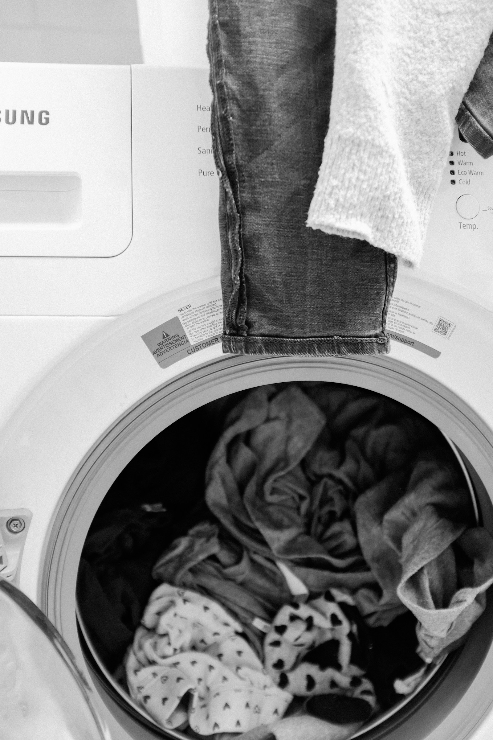 Laundry resting on the open door of a white front-load washing machine