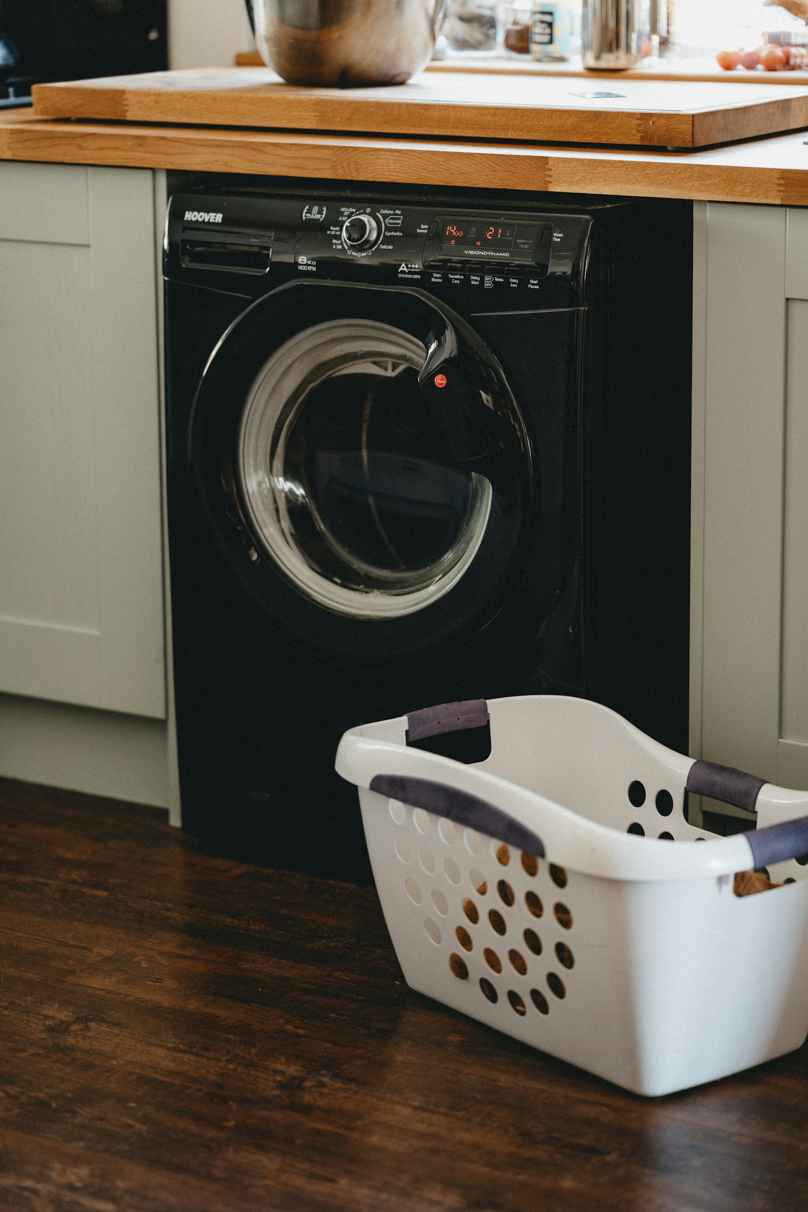 Black front-load washing machine beside a white laundry basket