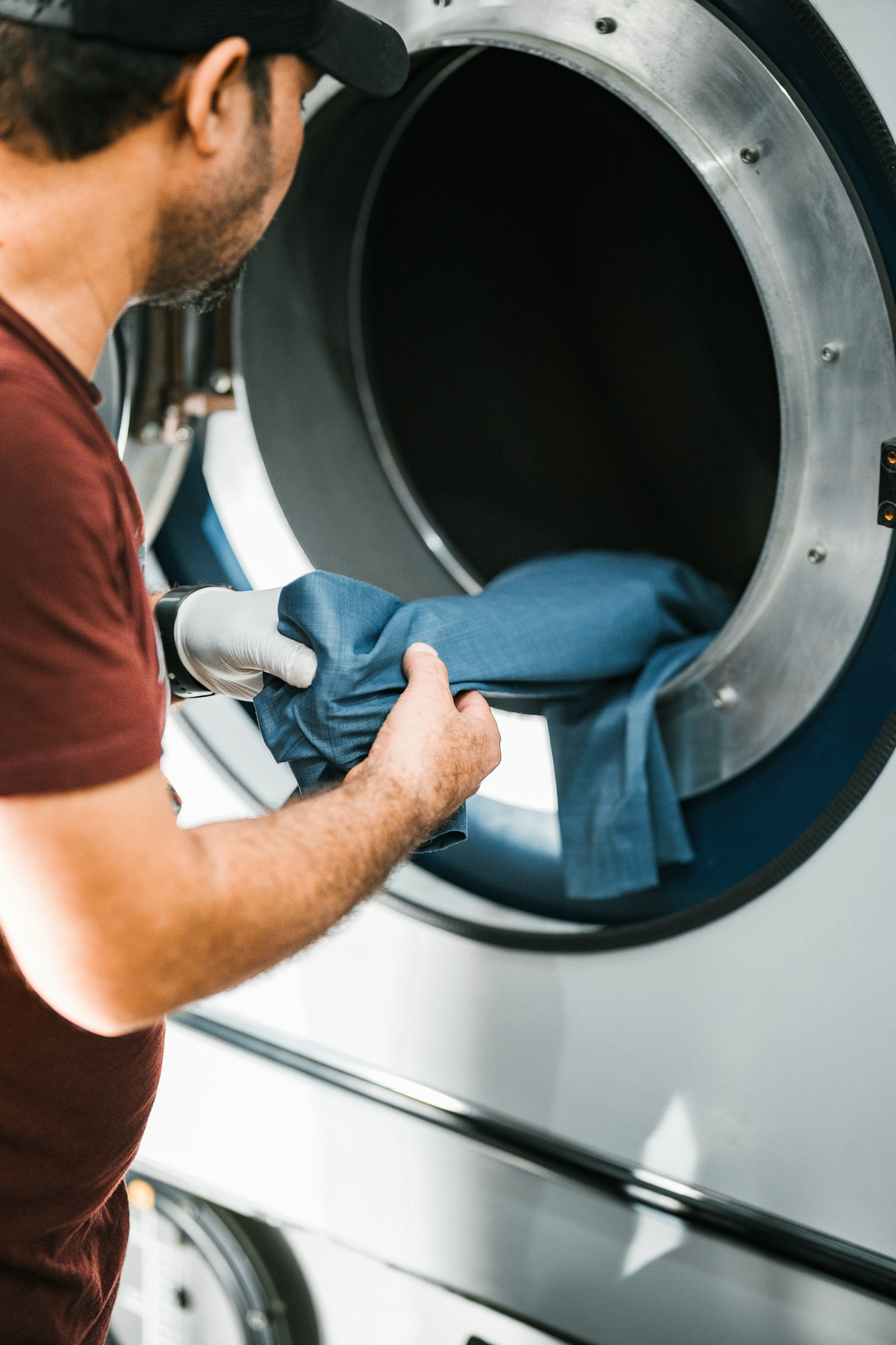 Man loading a blue cloth into a front-load washing machine at home