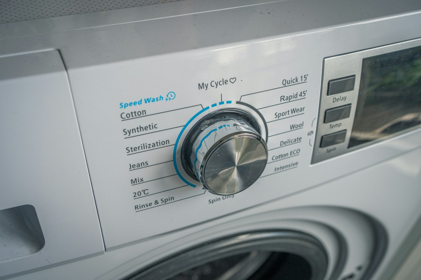 Close-up of a washing machine control panel with program dial and buttons